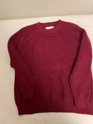 Maison Margiela tröja - Säljer en vinröd stickad tröja från Maison Margiela. Tröjan har ribbad struktur, rund hals och långa ärmar. Klassisk och enkel design med diskreta vita sömmar bak i nacken, perfekt för dig som gillar stilrena plagg med edge.