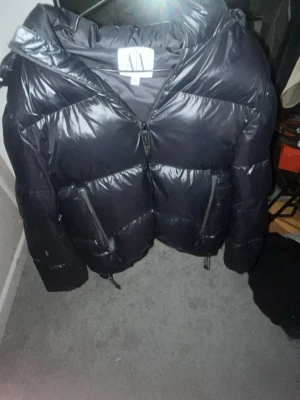 Svart pufferjacka från Armani Exchange -  Pris kan diskuteras. Säljer en svart pufferjacka från Armani Exchange i storlek M. Jackan har en glansig finish, dragkedja framtill och två sidofickor med dragkedja. Perfekt för kalla dagar. Ny pris 3000kr.