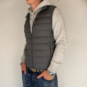 Uniqlo Väst - Nu har vi nöjet att erbjuda en Dunväst från det välrenommerade märket Uniqlo. Västen är i storlek Small och är i mycket gott skick utan några synliga defekter. Modellen på bilden är 180 cm lång och väger 75 kg, vilket kan ge en uppfattning om passformen