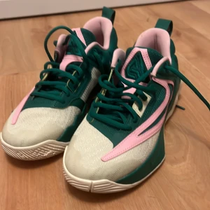 Nike sneakers grön/rosa strl 38,5 - Säljer ett par unika Nike sneakers i storlek 38,5 med grön och rosa färgkombination. Skorna har snörning, vit sula och detaljer i syntetmaterial. Perfekta för dig som vill sticka ut med en sportig och färgglad look.
