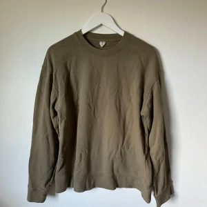 Olivgrön Arket sweatshirt i bomull, M - Enkel och stilren olivgrön Arket sweatshirt i 100% bomull. Tröjan har rund halsringning, långa ärmar och en relaxed passform. Perfekt för lager-på-lager och chill dagar. Snygg att matcha med jeans eller joggers. 3V14