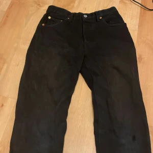 Svarta Levi's 501 Premium jeans - Svarta Levi's Premium 501 jeans med klassisk rak passform. Jeansen har fem fickor, silverfärgad knapp och nitar samt den ikoniska röda Levi's-taggen bak. Tillverkade i kraftigt jeanstyg som ger en tidlös look.