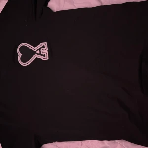 Svart t-shirt från Ami Paris - Svart t-shirt från Ami Paris med ikonisk hjärta-A patch broderad på bröstet. Klassisk passform och rund halsringning. Tillverkad i mjuk bomull som känns skön mot huden. Perfekt för en clean och stilren look.