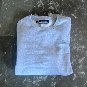 Ljusgrå sweatshirt från J.Lindeberg - Säljer en mjuk och snygg ljusgrå sweatshirt från J.Lindeberg med broderad logga på bröstet. Tröjan har rund hals, ribbade muddar och är tillverkad i mjuk bomullsblandning. Perfekt för en clean och avslappnad look. Aldrig använd och köpt på nk i present, passade ej mig. Vid frågor eller funderingar är det bara att höra av sig, pris går att diskutera😁!