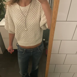 Vit stickad tröja från Lindex - Säljer en vit stickad tröja från Lindex i storlek S. Tröjan har ett luftigt, hålstickat mönster, bred ribbad mudd i hals och nederkant samt korta, lite puffiga ärmar. Perfekt till jeans för en chill och snygg look.