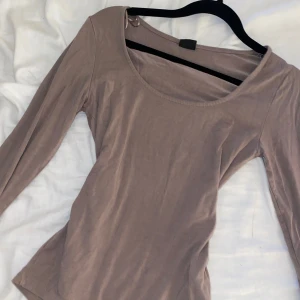 Beige långärmad topp Gina Tricot - Säljer en enkel och stilren beige långärmad topp från Gina Tricot. Toppen har rund halsringning och är figurnära i modellen, perfekt att matcha med jeans eller kjol. Tillverkad i mjuk bomullsmix för en skön känsla hela dagen.