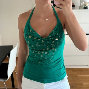 Grön halternecktopp - Grön mönstrad topp med knytning i nacken och öppen rygg. Materialet är väldigt stretchigt och det är dubbelt tyg över bysten.  Lappen är tyvärr bortklippt men gissar på storlek m💗