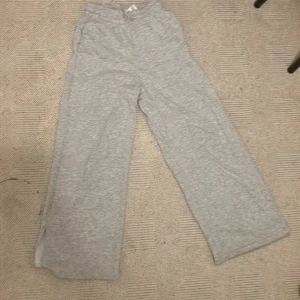 Grå mjukisbyxor från H&M wide fit - Superbekväma grå mjukisbyxor från H&M i wide fit-modell. Byxorna har resår i midjan och är tillverkade i en mjuk bomulls- och polyesterblandning. Perfekta för chill dagar och har en avslappnad look med raka, vida ben.