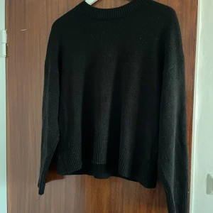 Svart stickad tröja från Divided - En svart stickad tröja från Divided med rund halsringning och ribbade muddar vid ärmslut och nederkant. Tröjan har en loose passform och är perfekt för lager-på-lager under kyliga dagar.