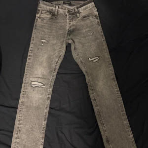 Grå Jack and Jones  jeans med slitningar - Säljer ett par grå Jack and Jones jeans med riktigt nice slitningar. Dem är knappt använda Max använda 5 gånger, Dem är storleken 32w/36L