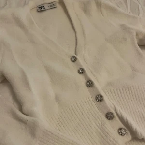 Stickad cardigan Zara - Vit stickad cardigan med knappar från Zara. Knappt använd och i jättefint skick. Storlek S 💕