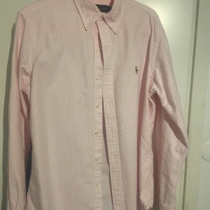 Ralph Lauren Skjorta - Säljer nu min vit och rosa randiga Ralph lauren skjorta som är perfekt nu till våren och sommaren. Den är i utmärkt skick utan skador. Den är i storlek M, har du frågor skriv privat 