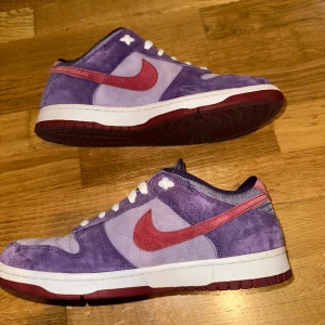 Nike Dunk Low Plum - Använda men i bra skick orginallåda finns men är skrivet på. Fler bilder går att erbjuda efter förfrågan. Original skosnören medföljer. Kan vara något billigare vid smidig affär. Köpare betalar frakt.