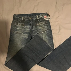 Lågmidjade Diesel Crossmi Jeans - Skit snygga lågmidjade bootcut jeans från diesel, i storlek 25. Köpte dom för ett tag sen men säljer dom nu för att dem aldrig har kommit till användning. Jag är 170 och de passar bra i längden. Dom är helt oanvända och i perfekt skick🥰 