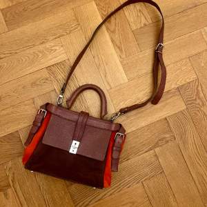 Burgundy color with red, unfoldable shoulder strap, great condition. Original item with the tag. Suede.