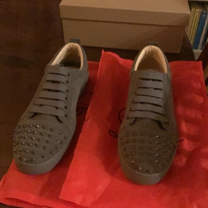 Gråa Christian Louboutins - Säljer min lillebrors Loubs pga för liten storlek. Har används en gång inomhus, aldrig ute. Dom är i storlek 42 men passar mig som har 43. Om ni har frågor om pris eller annat så fråga på!:)