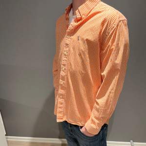 Säljer en snygg Ralph lauren skjorta i ett orange rutigt mönster. Storlek L passar M. Inga defekter på skjortan så den är i bra skick. Osäker på äkthet därav de låga priset. Han på bilden är 183cm. Nypris runt 1300, mitt pris 279. 