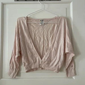 Kofta i rosa - Kort kofta med kortare ärm i ljusrosa. V-ringad och knäpps med två knappar. Aldrig använd, i fint skick. Skrynklig då den legat ihopvikt med andra kläder. Skriver inte ut märke med risk att inlägget blir borttaget.