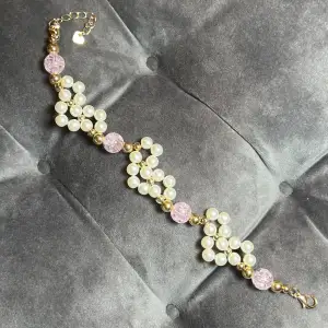 Sött pärlarmband med vita pärlor i hjärtform med rosa och guld pärlor och guldigt spänne. Justerbar passform mellan 20-25 cm.
