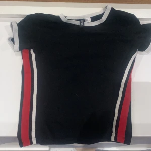 T-shirt med ränder  - Hm Storlek xs   Svart t-shirt med röda och vita ränder på sidan   Bra skick 