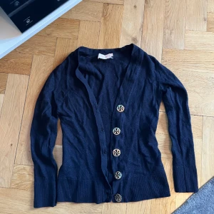 Tory Burch kofta - Marinblå kofta i merinoull från Tory Burch. Köpt på Jackie för ca 2.000kr.  Det står XS men den är mer som en XXS. Sytt igen ett litet hål på ärmen.