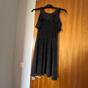  Glittrig festklänning -  Säljer denna jättefina festklänningen från Lindex har aldrig använt den hära därför säljer jag den för Lite Dyrare den är jättebra skick helt ny Den är svart Med glitter som inte faller av den är skön och mjuk perfekt för en festklänning på sommaren