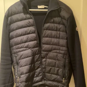 Moncler cardigan  - Tjena, vi säljer nu denna feta cardiganen som är perfekt nu till våren och kalla sommar kvällar, skick 9/10, 2 lagade hål som du kan se på näst sista bilden. Strl L, vid någon fundering är det bara att höra av sig, priset är ej hugget i sten! Mvh F&J
