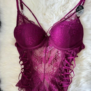 Body med spets och snören - Jättefin body som tyvärr aldrig kommit till användning och inte min stil längre. Prislappar kvar, storlek 75B.  