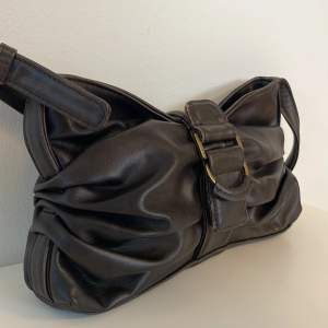 Brun handväska från Zara med vintage inspirerad stil, aldrig använd. 25cm längden & 17cm höjden.  Spänne med knapp på utsidan, dragkedja och ett litet innerfack. Bandet är ungefär 25cm så fungerar fint att ha över axeln, går även att justera bandet.