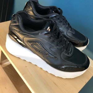 Fila sneakers  - Jättefina sneakers i svart skinn med en vit hög sula.  Sparsamt använda.  Nypris 999:-. Kan skickas.