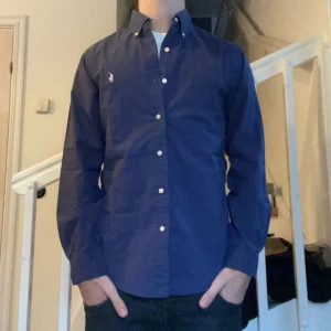 Ralph Lauren Skjorta  -  Säljer nu min riktigt snygga Polo Ralph Lauren Skjorta i bra skick. Har två små märken vid bröstet, där av det låga priset. Mörkblå med rosa Ralph Lauren Märke🙌 Storlek Small. Skriv vid intresse eller fler frågor✅