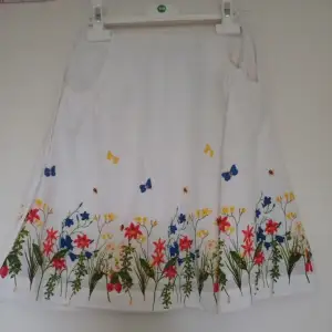 Fin vit kjol med sommarmönster från Åhléns. Kjolen har fickor och och en tunn innerkjol. Fint skicka säljer pga att den är för liten. 100% bomull. 