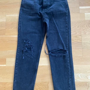 Svarta jeans med hål på knäna i strl 36 från Zara - Svarta jeans med hål på knäna i strl 36 från Zara.  Mått Midjan: ca 36 cm Från grenen och ner: ca 70 cm  Material: 100% bomull   Använda vid ett par tillfällen och i fint begagnat skick.  Kommer från ett djur och rökfritt hem