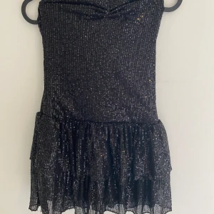 Svart of-shoulder mini paljettklänning  - Helt ny klänning med lappen kvar, passar storlek XS/S, ganska kort i rumpan. 