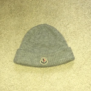 Moncler mössa - En fräsch moncler mössa. Har använt den ett tag men nu vill jag sälja den. Kommer med tags och påsen som den kom i. En liten defekt på ovansidan, dm för bilder😁