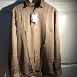 Skjorta från Ljung by Brothers - Jag säljer en helt oanvänd sandfärgad skjorta från Ljung by Brothers. Kvaliteten är hög och sitter bekvämt. Anledning till att jag säljer är att skjortan är någorlunda stor. Perfekt till sommaren och riktigt snygg färg. 