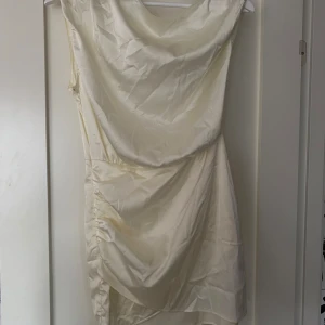 Champagnefärgad klänning - En elegant champagnefärgad klänning med draperad design. Klänningen har en ärmlös stil och är knälång. endast testad