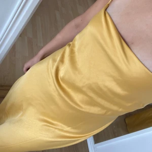 Silkesklänning - Säljer denna fina silkesklänningen ifrån Meshki, den är i en guldig/gul färg! Den är i en storlek L men passar mig som har S/M, perfekt i längden på mig som är ca 1,70. Storleken går att ändra mycket själv i ryggen när man knyter den! Prislappen kvar