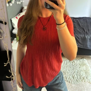 Röd t-shirt topp - Röd, höstig, texturerad t-shirt topp från Cubus i storlek XS (fungerar på XS-M skulle jag säga). Toppen har sydda kanter samt har använts varsamt. Färg samt textur på tröjan visas tydligast på sista bilden! Material: 100% polyester. :)