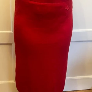 Lammullskjol! - Lång pennkjol (75 cm) i röd lammull, fodrad. Sprund med knappar bak. Ylletvätt 30 grader el kentvätt. Enstaka noppor men mycket välskött.