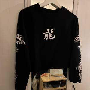 En svart croppad tröja med kinesiskt motiv av drakar från SHEIN!🌟Supersnyggt att ha en vit skjorta under🙏🏻  Storlek står ej, men är uppskattningsvis en S!💓