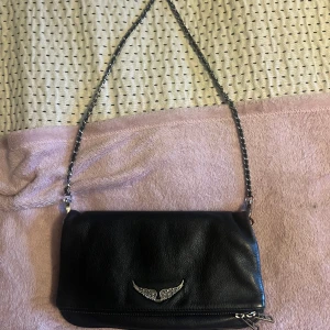 Svart zadig voltaire väska - En svart väska från zadig voltaire, i den vanligaste modellen och storleken.  Köpt för fem årsedan i Italien, så där av har den blivit  lite rostig på kedjan under dessa år jag använt den. Ändå bra skick på väskan. Nypris 3200kr. Kvitto finns.