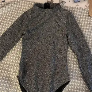 Glittrig body från H&M i storlek XS. Perfekt partytopp med öppen rygg.