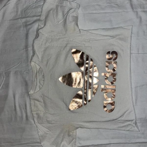 Adidas Croptop - Oanvänd vit kroptop med tryck från adidas. Mindre fläck på baksidan på ena axeln har uppkommit på vinden men inget som synns mycket. Frågor? Skicka ett medelande 😊