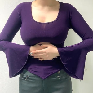 Lila tröja med Flared armar - Lila stretchig tröja med flared armar. Luftigt material. På den andra armen finns tyvärr bara ett lila band och inte två som på den andra