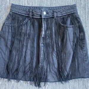 Ny gråsvart jeanskjol med fransar från Missguided i strl 40  - Ny gråsvart jeanskjol med fransar från Missguided i strl 40   Ny, aldrig använd   Mått Midjan: ca 37 cm Total längd: ca 40 cm  100% bomull   Kommer från ett djur och rökfritt hem. 