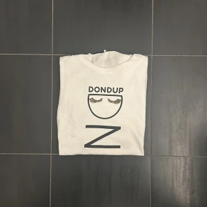 Dondup T-shirt - En riktigt fet Dondup T-shirt med tryck, unik och perfekt inför säsongen! Den är i riktigt bra skick, sparsamt använd men liten defekt där metall stycket sitter löst (bild 4). Hör gärna av er vid flera frågor och funderingar! 