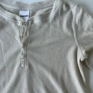 En långärmad beige tröja med knappar från Kappahl. Storlek 146/152 (passar någon som bär XS)