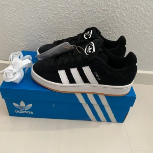 Nya Adidas Campus 00s - 995 kr - Adidas Originals Campus 00 s j Storlek: 36 2/3 Färg: Svarta (Core Black / Cloud White / Cloud White) Ingår både vita och svarta skosnören.  Nya och oanvända. Ligger kvar i kartong. 