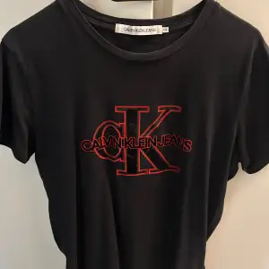 Svart CK t-shirt med rött sammet tryck. Storlek XS